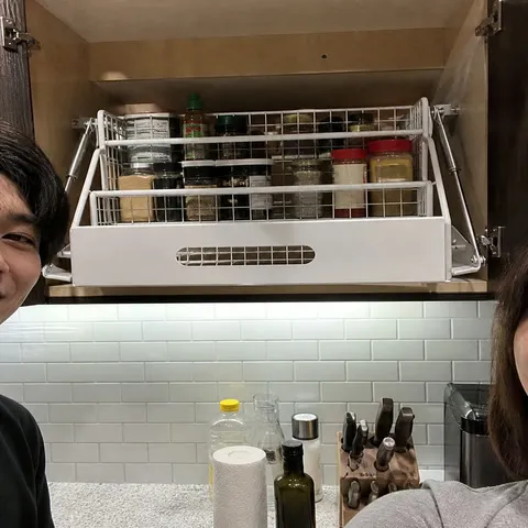 White pull-down rack raised inside a compact apartment kitchen cabinet