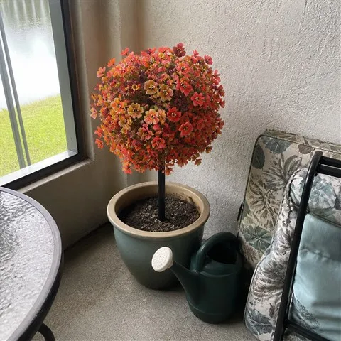 Artificial flower topiary in a ceramic planter on a covered patio