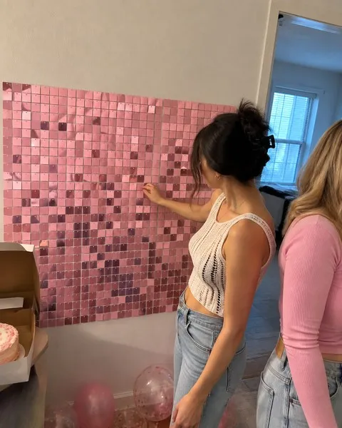 Friends touching a pink shimmer backdrop in an apartment