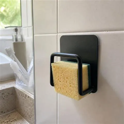 Black holder organizing a cleaning sponge near a bathroom sink