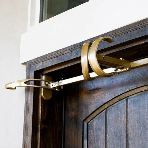 Close-up of the gold adjustable hanger and its twin center hooks above a wooden door