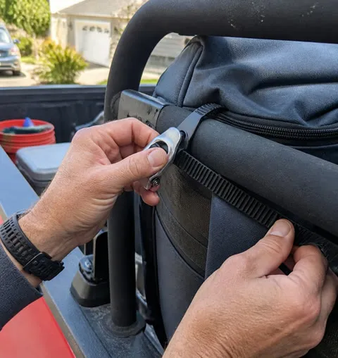 Hands fastening a utility strap around a truck gear bag