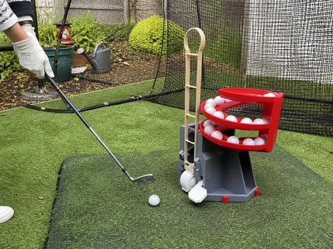 Red and charcoal dispenser next to a backyard practice net