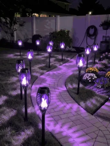 Solar flame torch lights being installed and glowing along a garden path