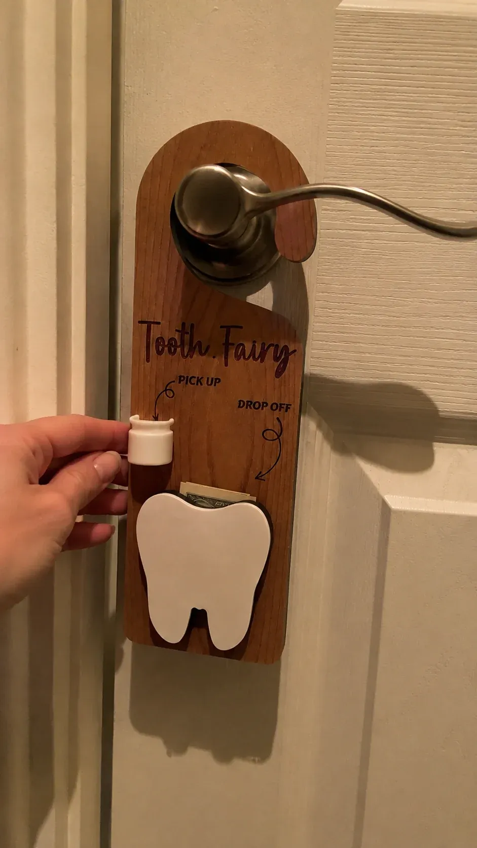 Customer photo of the Tooth Fairy door hanger on a lever-style interior door handle in warm evening light
