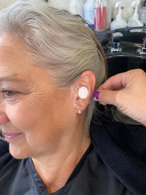 Older adult using a clear ear cover before a salon shampoo