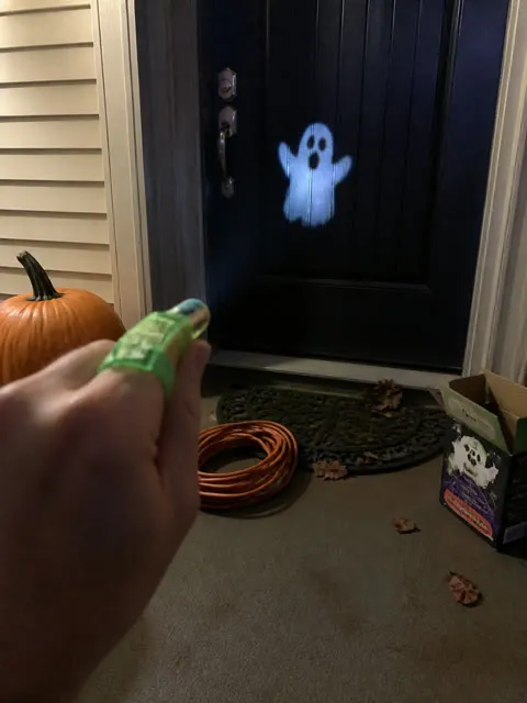 Green finger projector casting a ghost on a front door