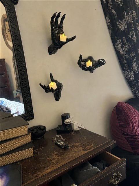 Black hand candle holders above a vintage bedroom dresser