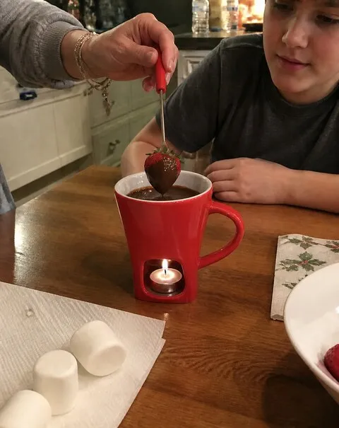 Parent and child using a red chocolate fondue mug at the kitchen table