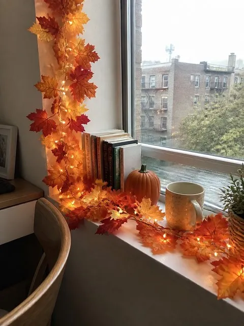 Glowing maple leaf garland decorating a compact apartment window nook