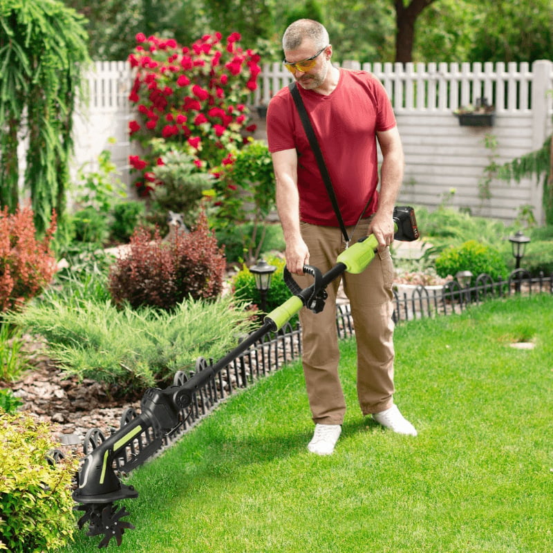 Gardener using the cordless tiller along a narrow garden bed