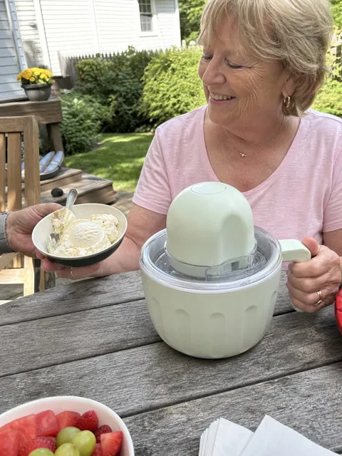Older customer enjoying homemade vanilla ice cream beside the maker outdoors