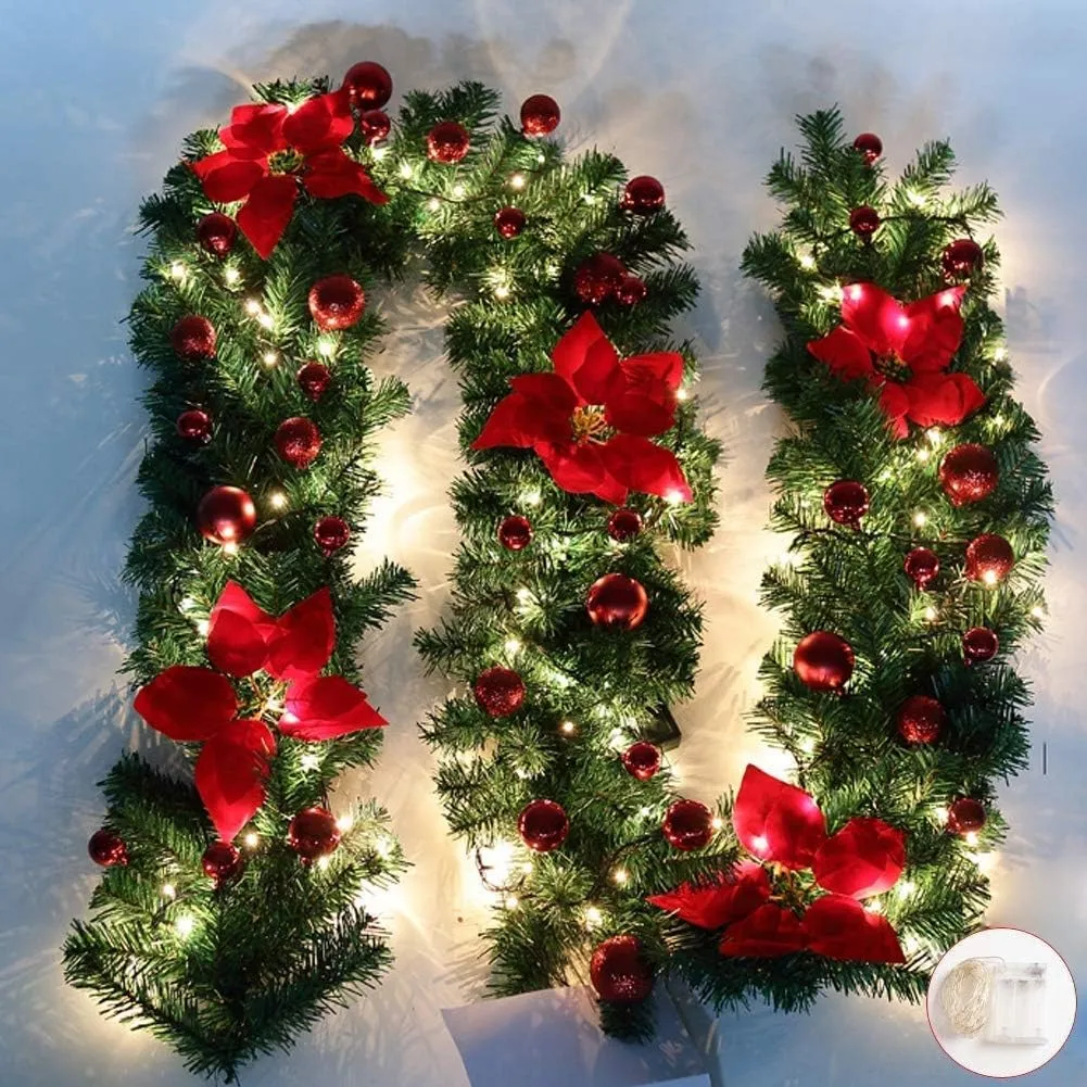 Close product view of green Christmas garland with red poinsettias ornaments and warm lights