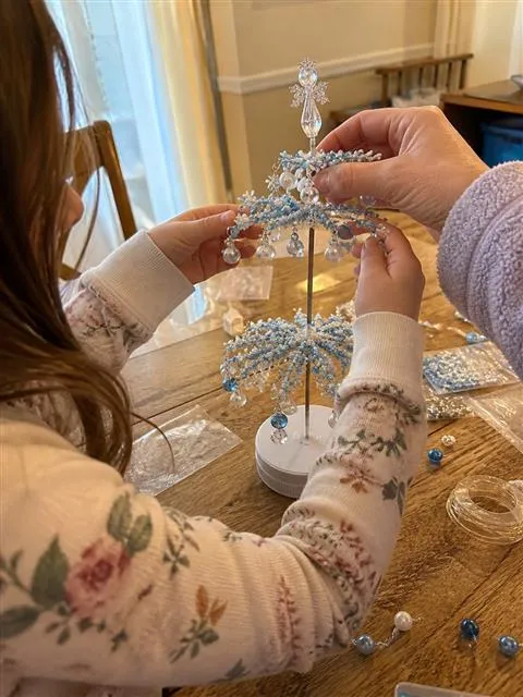 Family hands assembling the winter beaded tree