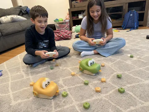 Two siblings racing the crocodile toys on a living-room rug