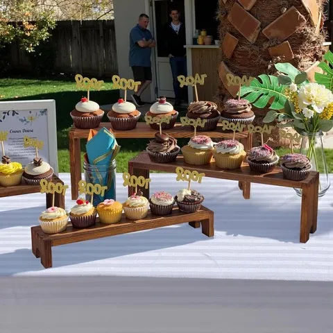 Four wood risers displaying cupcakes at an outdoor celebration