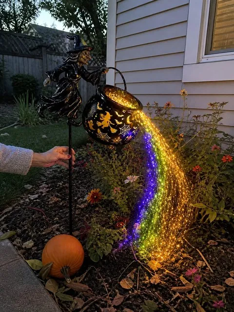 Witch cauldron light glowing in a suburban flower bed