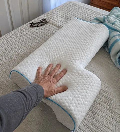 Hand pressing the slow-rebound pillow in a guest room