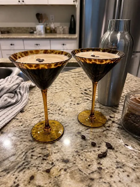 Two amber tortoiseshell martini glasses with espresso martinis on a home kitchen counter