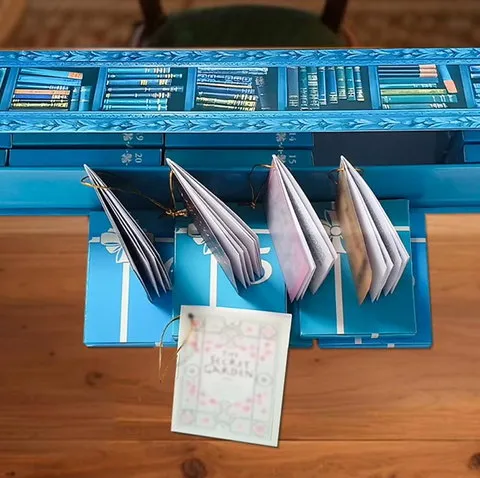 Four open miniature books displayed in front of the blue advent calendar