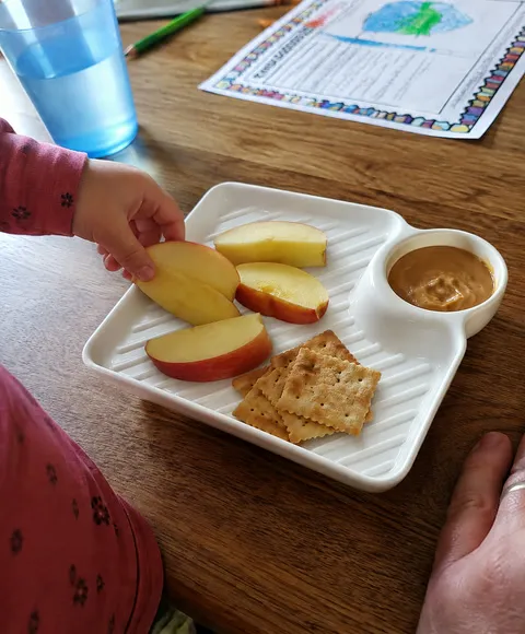 Apple slices and crackers with dip on a family snack table