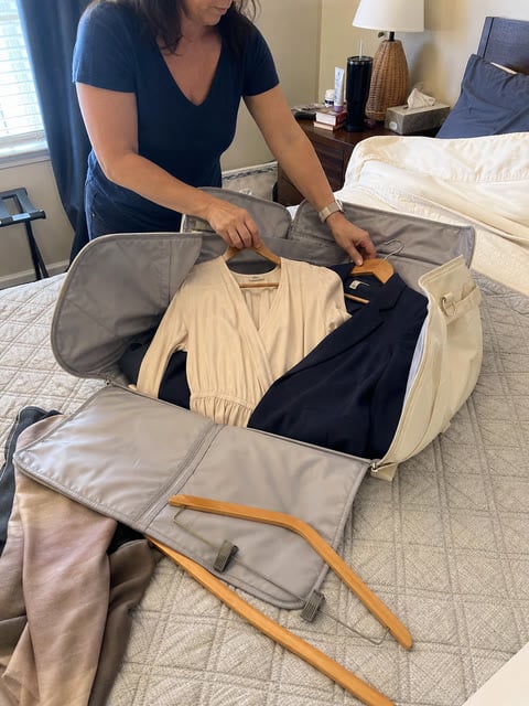 Traveler arranging a dress and blazer in the open garment bag