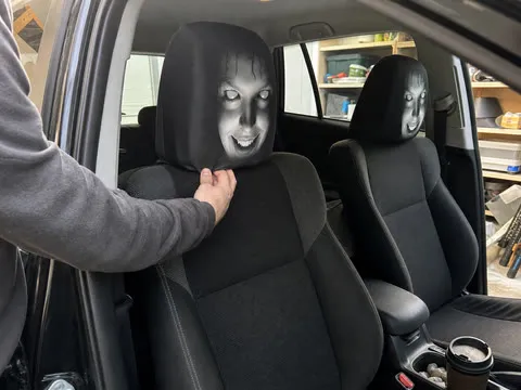 Casual garage photo showing a scary headrest cover being installed