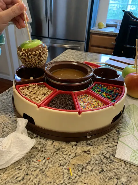 Parent and child making a caramel apple in a home kitchen