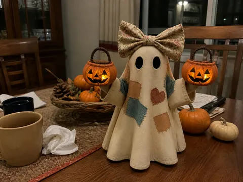Double-pumpkin patchwork ghost on a cozy nighttime dining table