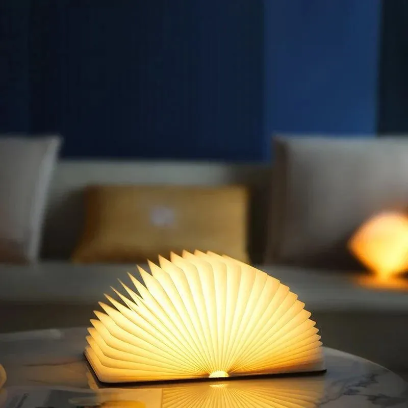 Compact folding book light casting a warm glow on a side table