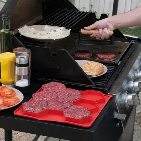 Rectangular red patty mold beside a backyard grill