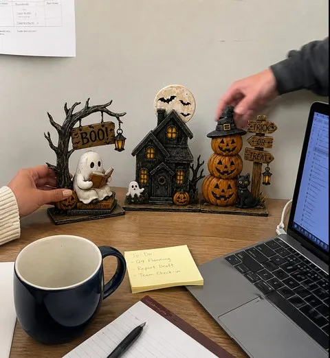 Coworkers arranging a three-piece Halloween figurine set on an office desk