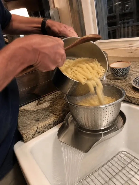 Pasta being drained into the elevated colander