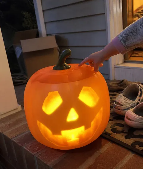 Child reaching for the controls on a porch pumpkin display