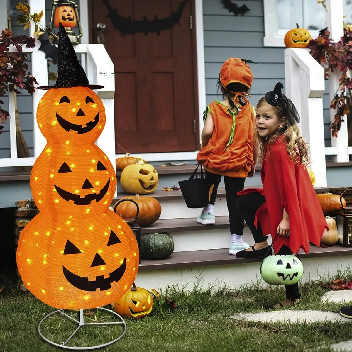 Glowing stacked pumpkin lantern decoration beside a family porch