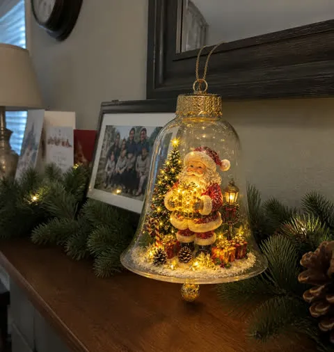Santa light-up bell ornament glowing on a family mantel