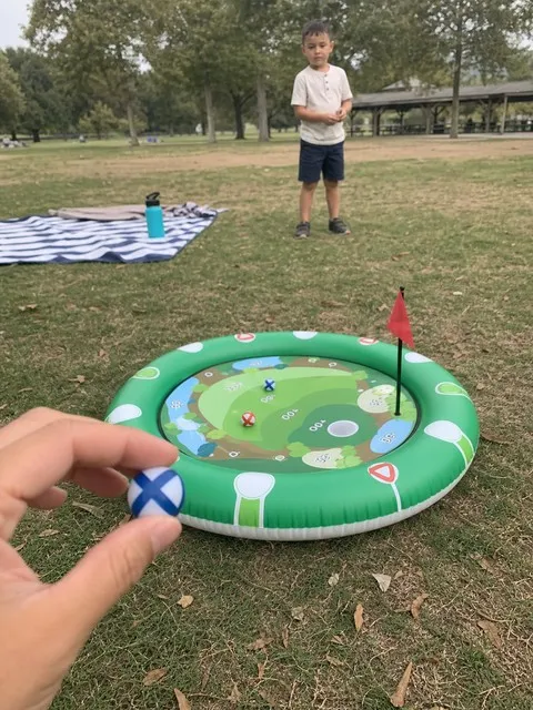 Grandparent and child playing with the golf target at a park