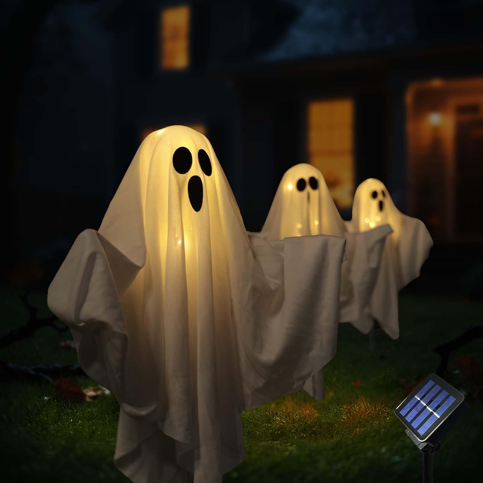 Three warm-white solar ghost lights glowing on a front lawn