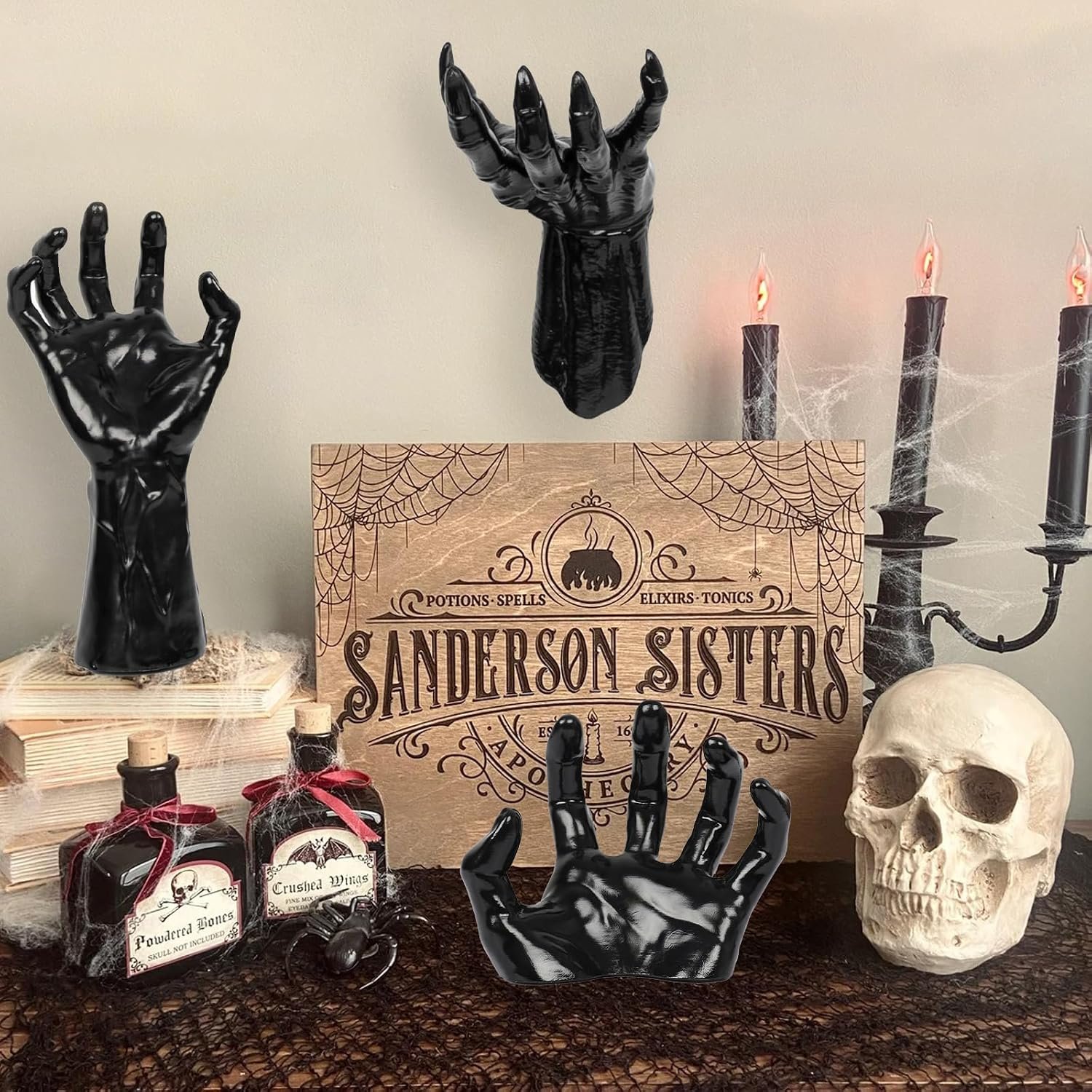 Three black hand candle holders styled in a gothic room