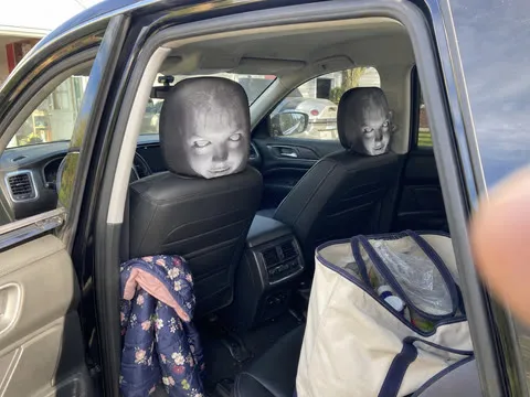 Casual driveway photo of scary face covers on two car headrests