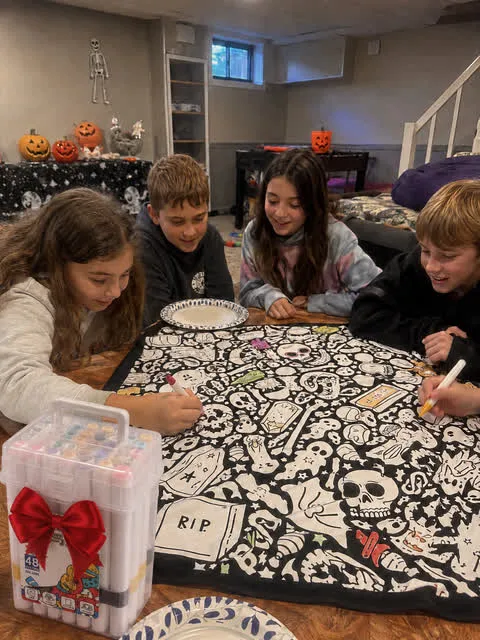 Family group coloring the blanket at a Halloween gathering