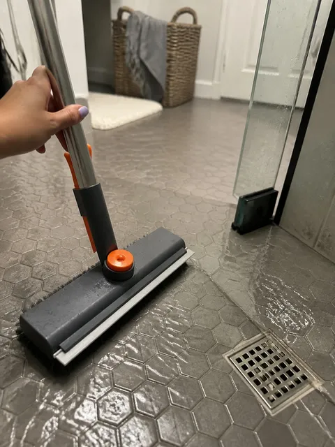 Floor brush pulling water toward a shower drain