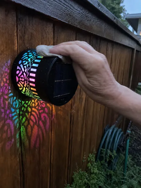A customer wiping rain from a colorful solar mandala light