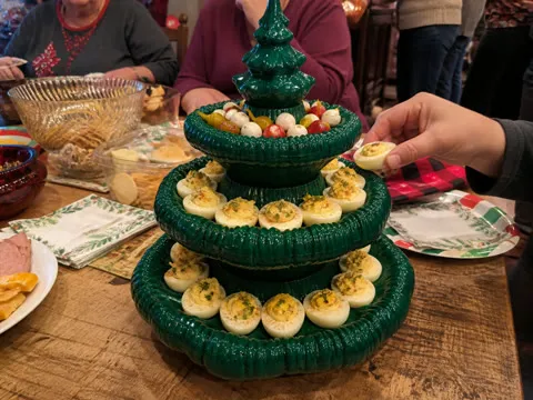 Family potluck with guests reaching for deviled eggs from the platter