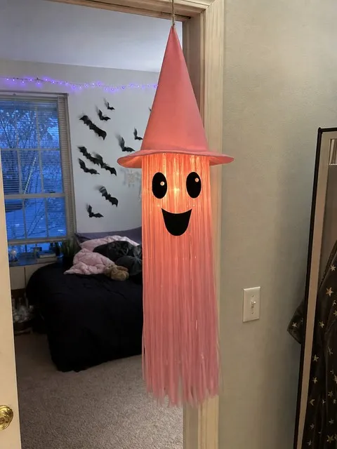 Pink light-up tassel ghost hanging in a decorated bedroom doorway
