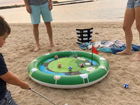 Family playing with the inflatable golf target on beach sand
