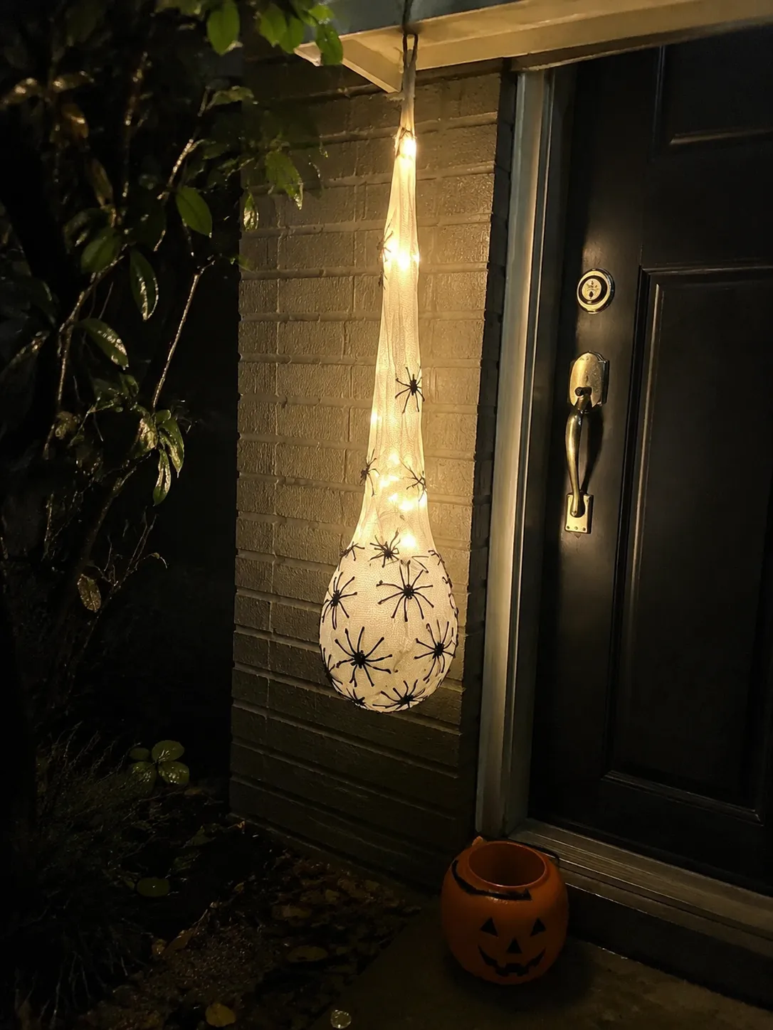 Warm glowing spider egg sac beside a front door