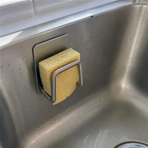 Silver sponge holder mounted inside a kitchen sink