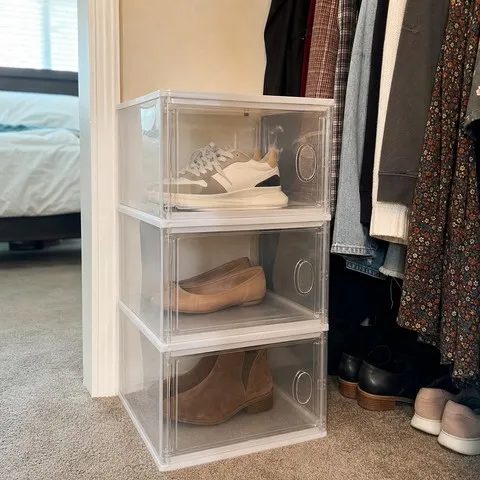 Three clear shoe storage boxes stacked in a bedroom closet