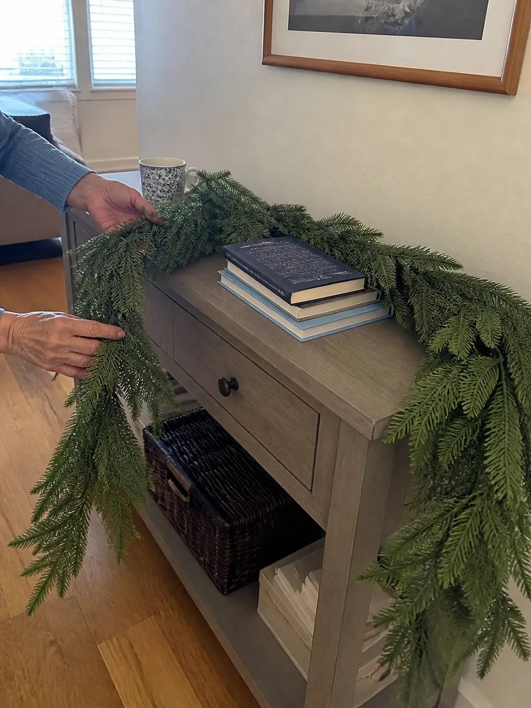 Hands shaping green garland over a console table